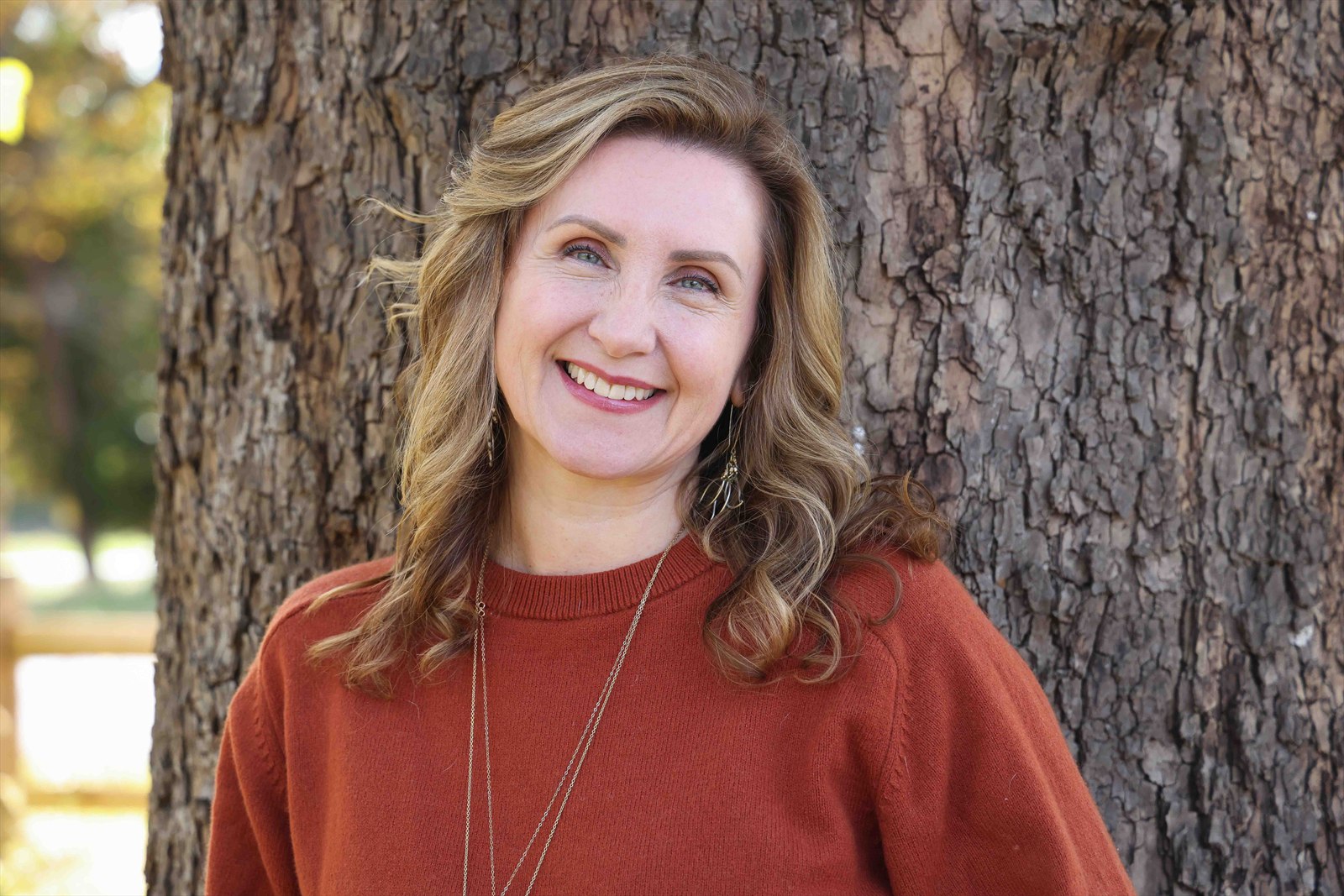 Christine Dorsey, intuitive energy healer and Reiki Master, smiling beside a tree